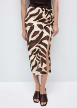 Falda midi de viscosa con estampado animal print en tonos marrones y crema. Presenta un diseño recto con detalle drapeado lateral y una abertura pronunciada en la pierna. Cuenta con cierre de cremallera invisible en la parte posterior.