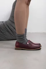 Mocasín de cuero vacuno en color marrón, con diseño bitono que combina texturas lisas y con grabado tipo cocodrilo en el empeine. Cuenta con detalle de estribo clásico y suela plana con vira en contraste.