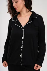 Pijama de dos piezas color negro con ribetes blancos, compuesto por una camisa de manga larga con botones y cuello tipo solapa, y un pantalón largo con cintura elástica.