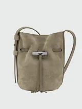 Cartera tipo bucket XS Longchamp de la línea Le Roseau Velvety, confeccionada en cuero marrón con textura gamuzada. Cuenta con cierre de cordón ajustable con detalle de bambú metálico plateado y correa ajustable para el hombro.