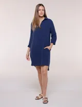 Vestido corto blanco de algodón, marca Dash, con cuello camisero, escote en V y bolsillos laterales. Presenta mangas tres cuartos y calce holgado con ruedo irregular.