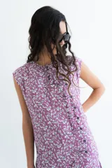 Vestido corto sin mangas en color rosado con estampado floral en blanco y negro. Presenta una cartera de botones asimétrica en el frente y detalle de volado fruncido en el ruedo. Confeccionado en algodón liviano.