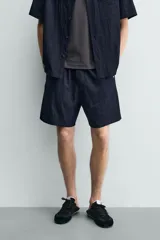 Bermuda relaxed fit de color azul marino confeccionada en tejido fluido con mezcla de viscosa, cintura elástica con cordón interior y bolsillos frontales.