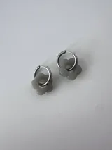 Aros de acero quirúrgico hipoalergénico con dije colgante en forma de flor gris.