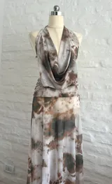 Vestido largo de microtul con estampado abstracto en tonos marrones y blancos, escote halter pronunciado, espalda descubierta y aberturas laterales en la cintura.