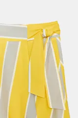 Falda midi tipo pareo de tiro medio, confeccionada en algodón con diseño de rayas verticales en tonos amarillo, gris y blanco. Presenta un bajo asimétrico y cierre lateral con lazada.