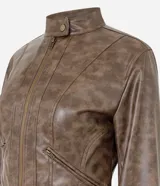 Campera biker de cuello alto confeccionada en poliuretano con efecto marmorizado. Presenta cierre frontal, bolsillos laterales con cremallera, recortes estructurados y detalles de botones a presión en el cuello y laterales.