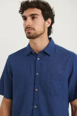 Camisa sport de manga corta, confeccionada en una mezcla de lino y algodón. Presenta cuello clásico, cierre frontal con botones de coco y un bolsillo aplicado en el pecho.
