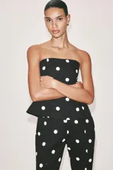 Mono largo de escote recto sin tirantes, con peplum en la cintura, perneras acampanadas y estampado de lunares.