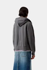 Campera con capucha de corte holgado, color gris oscuro efecto desgastado, con cierre frontal completo, cuello alto, bolsillos tipo canguro y mangas raglán. Presenta una pequeña etiqueta cuadrada con el logo de la marca en el bolsillo izquierdo.