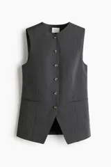 Chaleco largo de vestir color gris oscuro con finas rayas verticales, cuello en V y cierre frontal de botones. Presenta bolsillos delanteros ribeteados y abertura en la parte trasera inferior.
