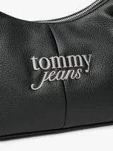 Cartera de hombro de poliuretano con acabado granulado y cierre de cremallera. Presenta una correa ajustable, un compartimento principal, un bolsillo interior con cremallera y el logo metálico de Tommy Jeans en la parte delantera.