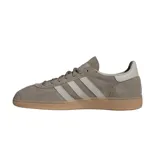 Championes adidas Handball Spezial inspirados en el modelo de 1979, confeccionados en gamuza gris topo con las clásicas tres tiras y refuerzo de talón en tono claro, inscripción lateral en letras doradas y suela de goma de tipo caramelo.