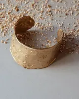 Brazalete rígido de diseño artesanal con textura irregular y acabado metálico, elaborado en bronce macizo.