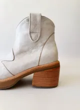 Botas texanas de cuero color gris claro, con caña baja, puntera cuadrada y taco de madera.