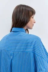Camisa de corte oversize con estampado de rayas verticales, cuello clásico, cierre frontal con botones y mangas largas con volumen.