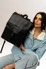 Mochila negra de cuero sintético con solapa superior y cierre con hebilla.