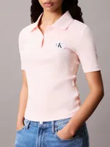 Chomba de Calvin Klein Jeans confeccionada en tejido de algodón con textura acanalada. Presenta cuello tipo polo con cartera de dos botones, mangas cortas y una insignia distintiva de la marca aplicada en el pecho.