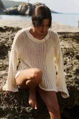 Sweater tejido color crudo, de manga larga y escote redondo. Tejido calado con caída relajada.