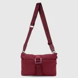 Cartera tipo bandolera de diseño plano y minimalista, confeccionada en material sintético resistente color bordó. Cuenta con una correa ajustable con el logo de la marca estampado, cierre principal superior y un bolsillo frontal con cierre asegurado por una hebilla decorativa.