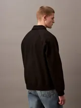 Sweater negro de Calvin Klein con cuello tipo chomba, cierre de cremallera parcial y logo "CK" bordado en blanco en el pecho.