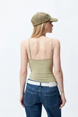 Body blanco de microfibra, corte minimalista, con breteles finos y frunces laterales entrecruzados en el torso.