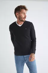 Sweater de tejido de punto color beige, con escote en V, mangas largas y puños y dobladillo acanalados. Presenta un pequeño logo bordado en el pecho.