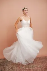 Vestido largo blanco de alta costura, con corset estructurado de tirantes finos con apliques florales y falda amplia de tul con brillo.