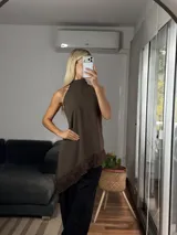 Musculosa de cuello alto con diseño irregular y bajo asimétrico, confeccionada en tela tipo cey con detalle de puntilla en el ruedo.