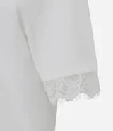 Remera de corte recto y calce confortable, confeccionada en algodón. Presenta cuello redondo y mangas cortas amplias con delicada aplicación de encaje en los bordes.