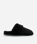 Pantufla abierta color negro, con textura acanalada en la parte superior y forro de peluche suave en el borde y el interior. Posee una suela de goma blanca.