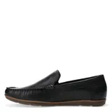 Mocasines de cuero color negro con costuras visibles en el empeine y suela plana de goma en tono marrón. Presenta un detalle metálico con el logo de la marca en el lateral.