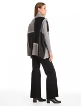 Polera tipo poncho de corte oversize, con cuello alto tejido y mangas largas con puños elásticos. Presenta un diseño geométrico de bloques de color en tonos beige, gris y tostado.