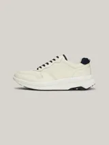 Zapatillas Tommy Hilfiger de cuero color blanco con detalles en azul marino. Presentan cordones azul marino, suela gruesa blanca y logo de la marca en el lateral.