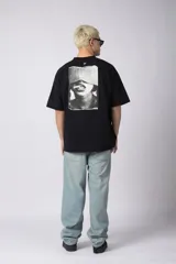 Remera oversize de algodón negro, con cuello redondo y manga corta ancha. Presenta un pequeño logo bordado en el pecho con un símbolo de prohibido fumar.