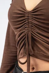 Crop top de manga larga color marrón, con escote en V y detalle de frunce central regulable mediante cordones.
