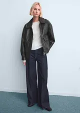 Jeans tiro alto wide leg con diseño de cinco bolsillos y cierre frontal de cremallera y botón.