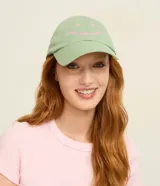 Gorra de sarga color verde con visera curva y bordado frontal con la frase "good days ahead" y detalles de flores en tono rosado.