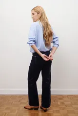 Camisa blanca de manga larga con cuello clásico, cierre de botones frontal y bolsillo de parche en el pecho.