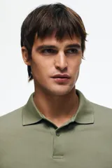 Remera polo H&M de manga corta en piqué de algodón, color verde militar, con cuello camisero y tapeta frontal de dos botones. Corte estándar para una silueta clásica y cómoda.