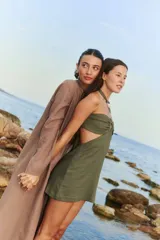 Vestido corto color verde militar, confeccionado en lino y rayón, con escote halter con arandelas metálicas, espalda semi descubierta y cierre invisible en la espalda. Se ata al cuello y espalda, adaptándose a la cintura.