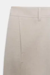 Pantalón de tiro alto color beige, con costuras marcadas en la parte delantera y cierre frontal de cremallera con botón negro a contraste.