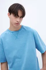 Remera color ladrillo, teñida en prenda con detalle en cuello, largo trasero más largo que delantero, tajos laterales, algodón lavado con textura extra suave, tela jersey pesado y calce oversize.