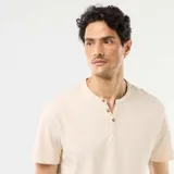 Remera de manga corta color beige, con cuello tunecino y cartera con botones frontales.