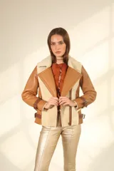 Chaqueta tipo gamulán de cuero color camel con interior y solapas de piel sintética en color beige. Presenta cierre frontal cruzado, correas ajustables con hebillas en los puños y en los laterales de la cintura.
