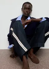 Jeans de corte wide leg y tiro bajo, confeccionados en tejido de algodón. Presentan un diseño largo con rayas laterales decorativas, trabillas para cinturón y cierre oculto de botón, gancho y cremallera.