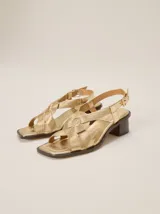 Sandalias de cuero metalizado color bronce, de taco bajo, punta cuadrada y tiras cruzadas en el empeine con textura acanalada. Posee tira al tobillo ajustable con hebilla metálica dorada.