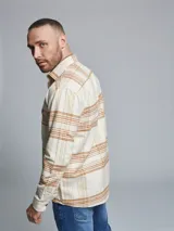 Sobrecamisa de manga larga con diseño a cuadros en tonos beige y marrón. Presenta cuello clásico, cierre frontal con botones y dos bolsillos en el pecho.