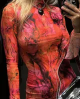 Vestido corto de microtul elastizado con estampado floral en tonos naranja, rosa y negro. Tiene cuello alto y mangas largas acampanadas.