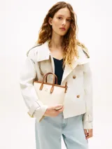 Cartera tote Tommy Hilfiger modelo TH Monoplay, color beige con estampado integral del monograma TH en relieve, asas superiores y correa bandolera extraíble de cuero sintético marrón. Cuenta con cierre de cremallera e insignia metálica del monograma en el frente.